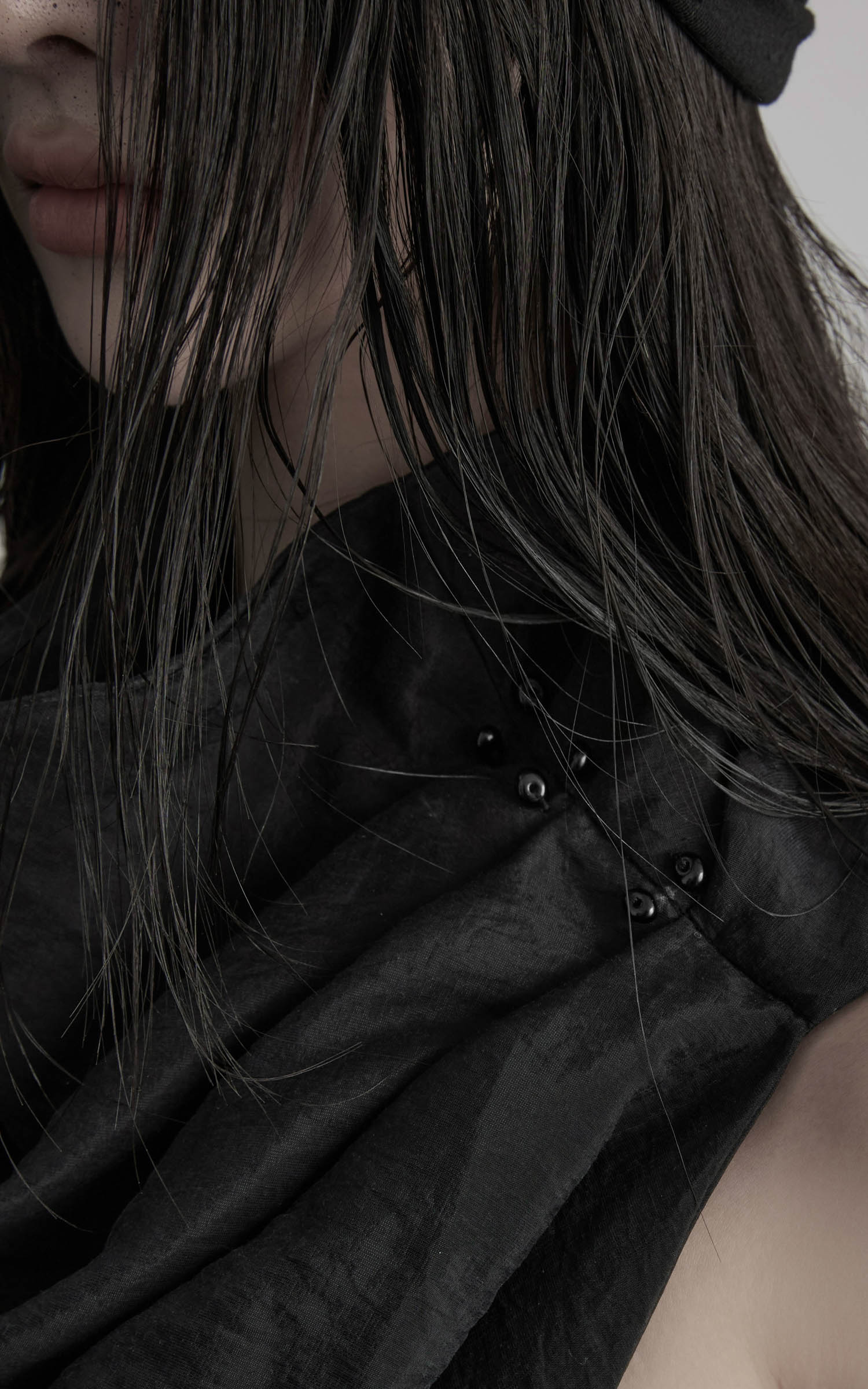 Close-up of black asymmetric drape scarf shawl with textured folds and hardware
