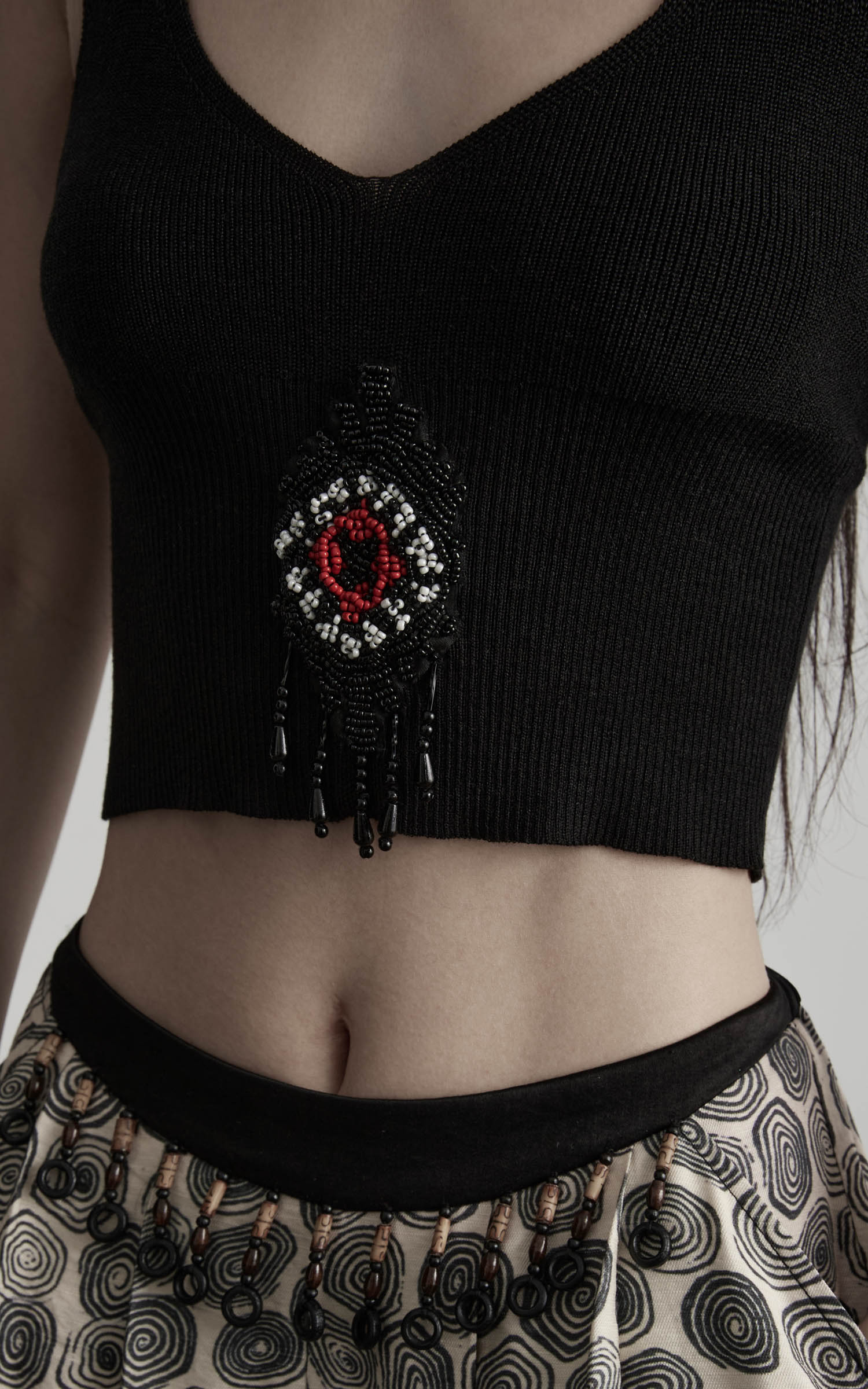 close-up of black beaded halter knit top with central motif detail