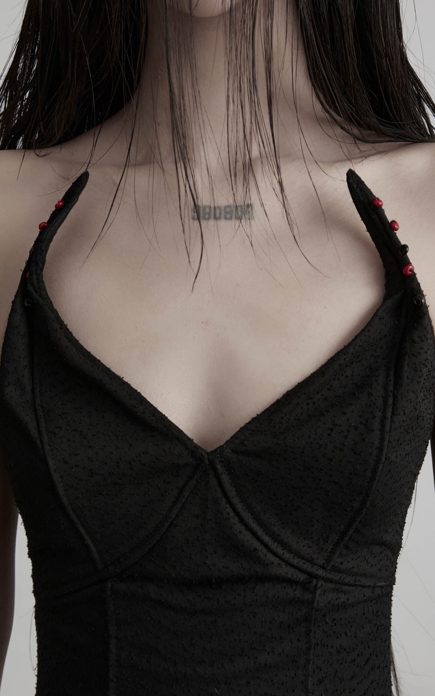 Close-up of black cotton bustier dress with stitched cups and bead straps
