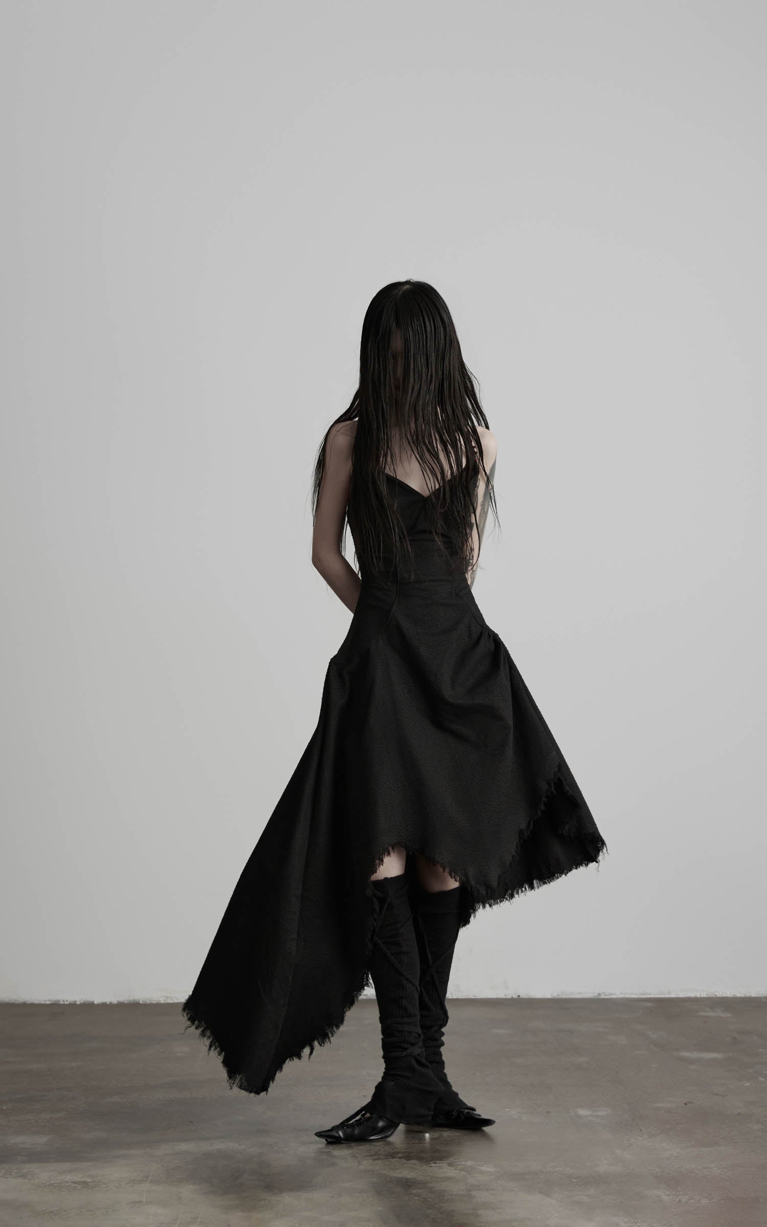 Black cotton bustier dress with asymmetric skirt drape front view