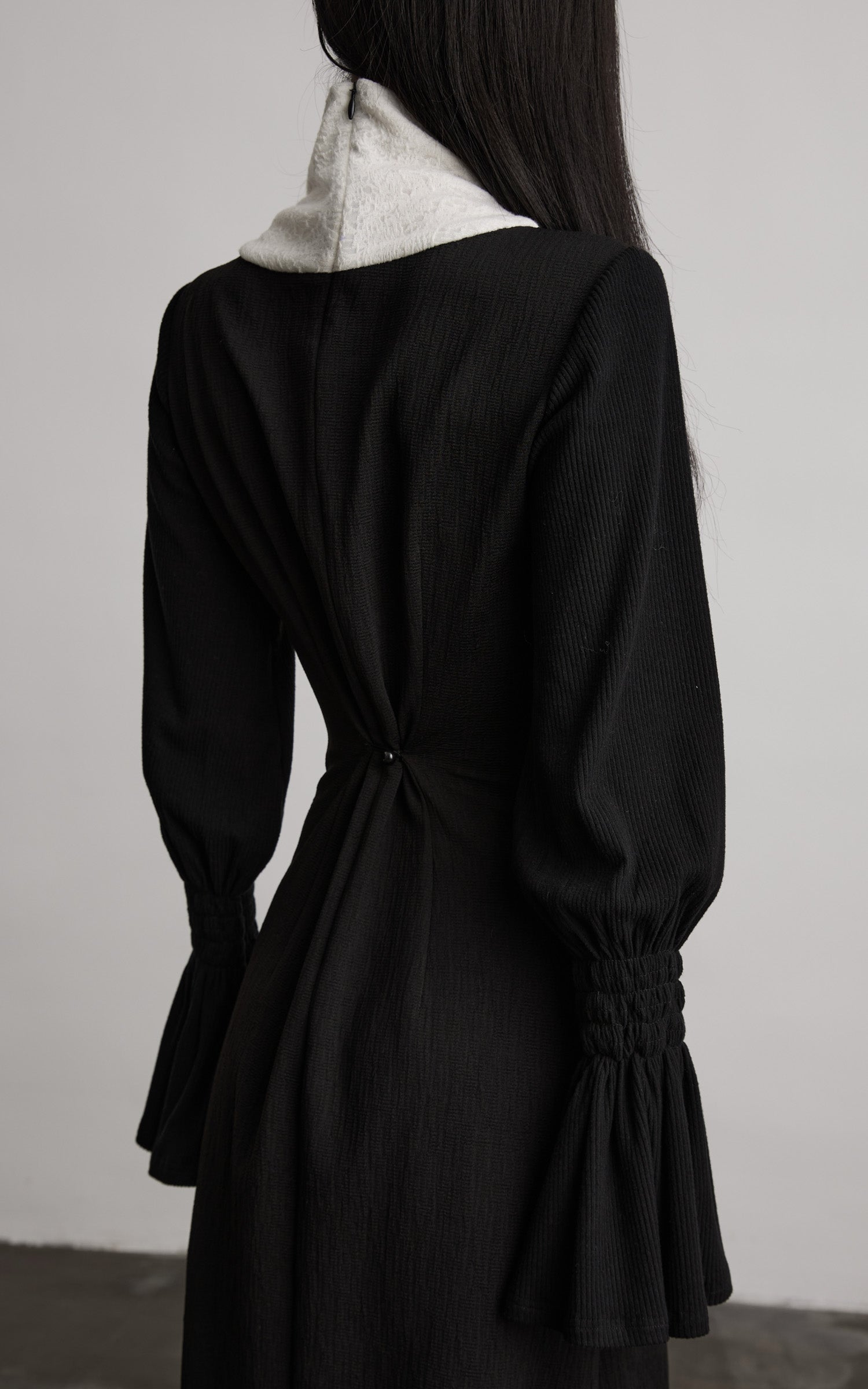 back view of black contrast panel dress with gathered waist detail