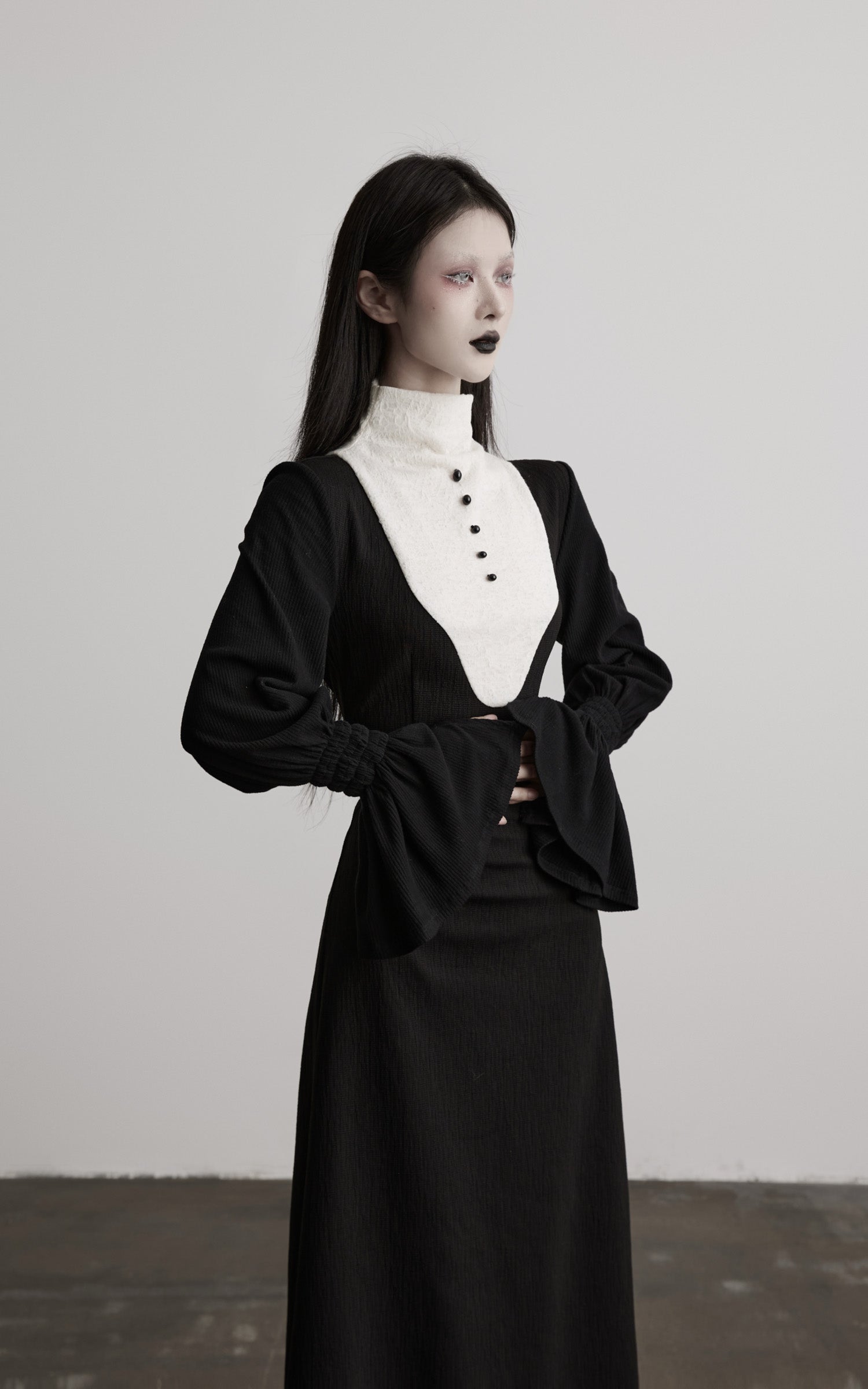 three-quarter view of black contrast panel high neck dress with long sleeves