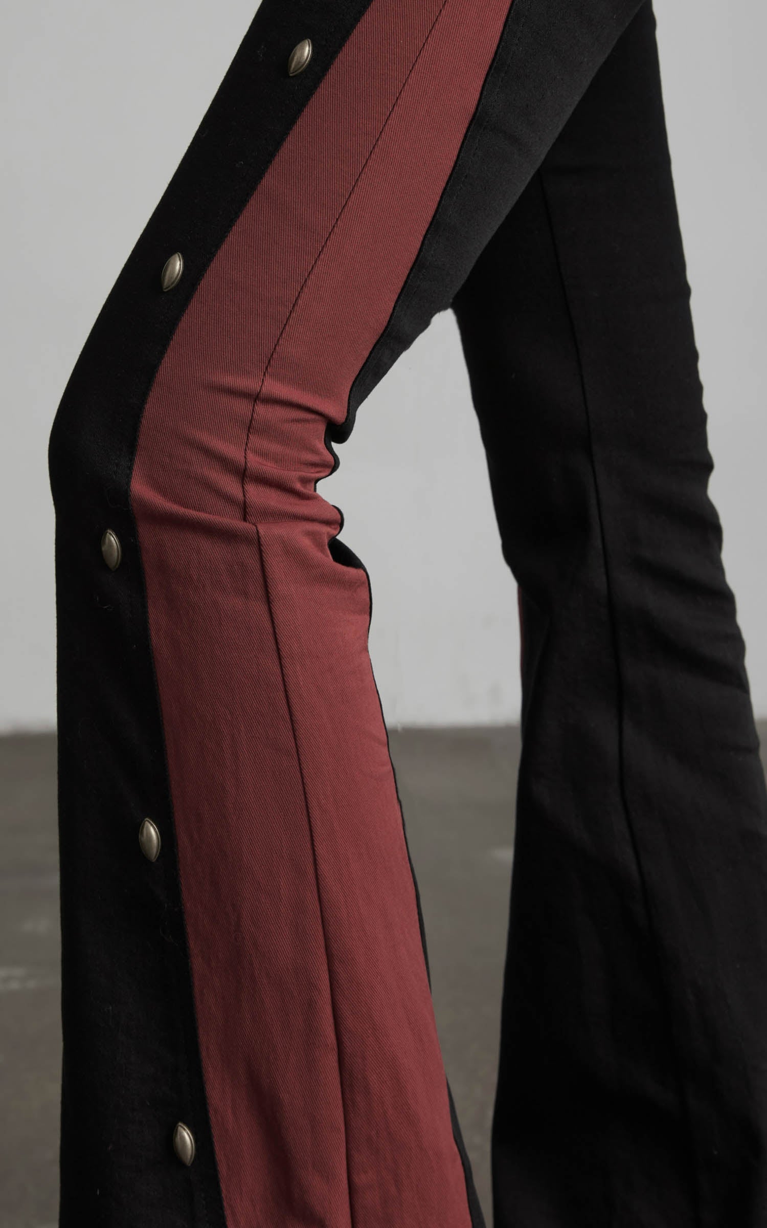 close-up of black flared pants with red contrast panel detailing
