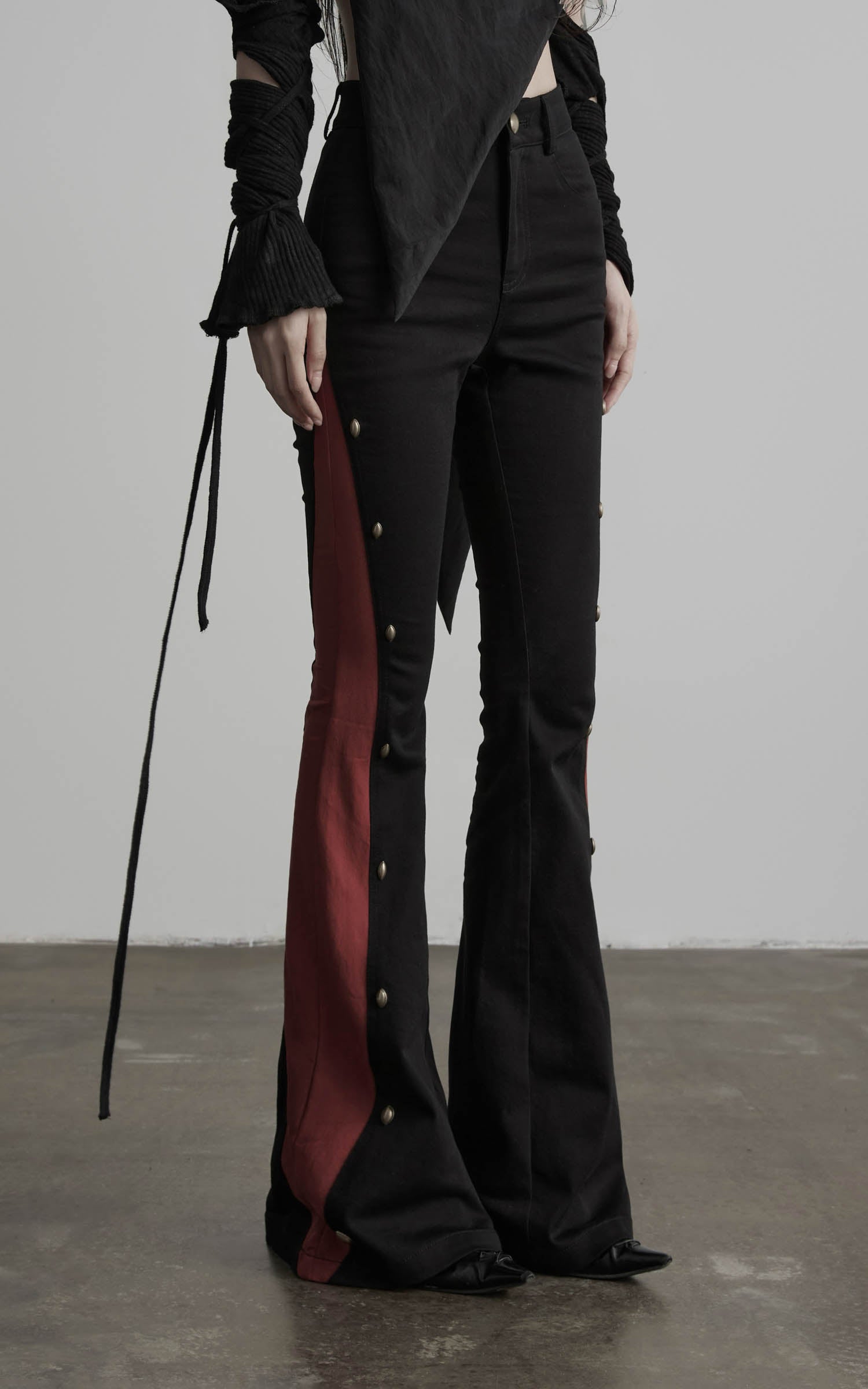 front detail view of black flared pants with red contrast panels