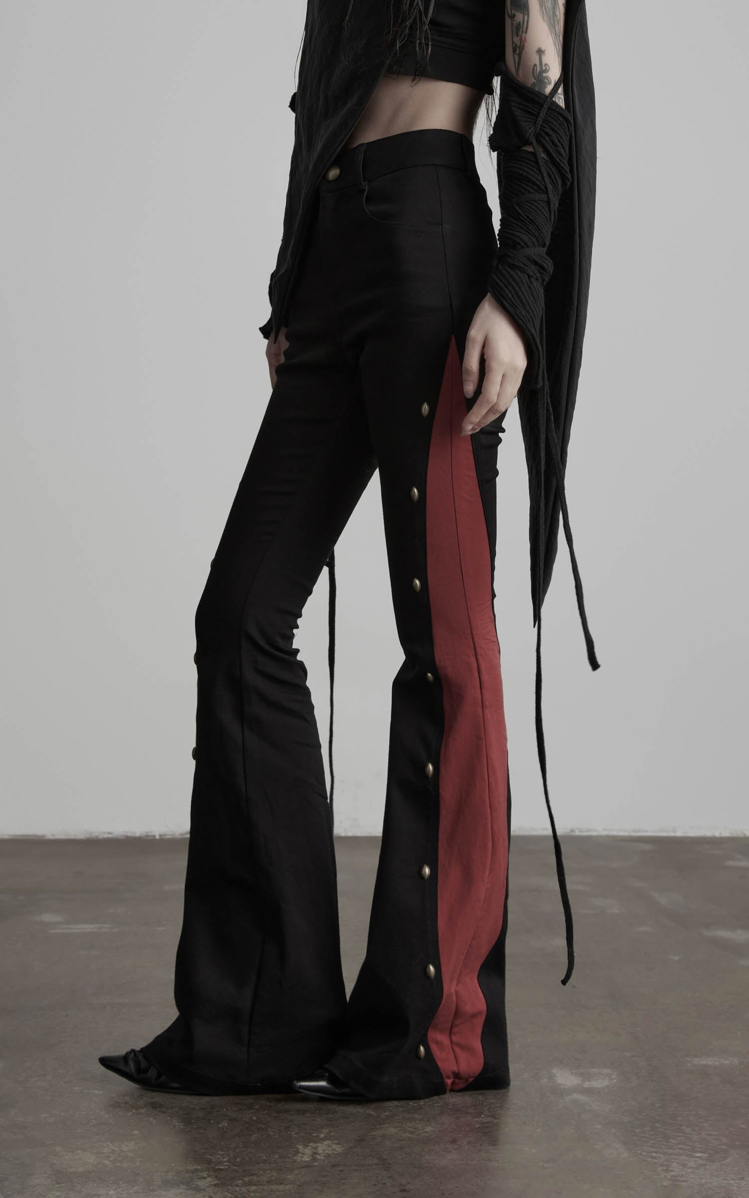 side view of black contrast panel flared pants with button trim