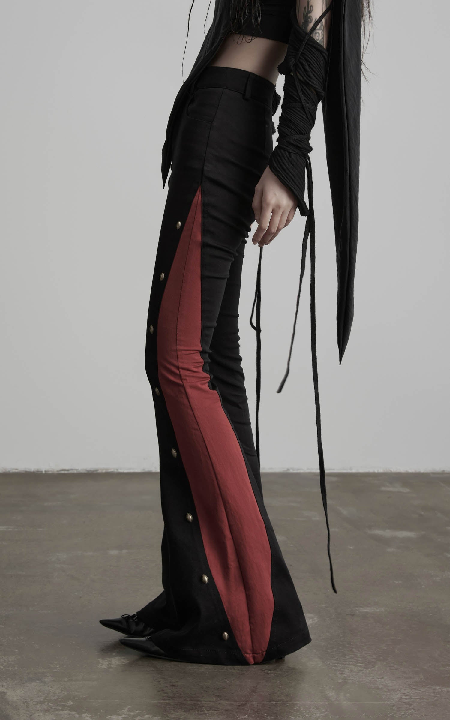 side view of black low-rise contrast panel flared pants with studs