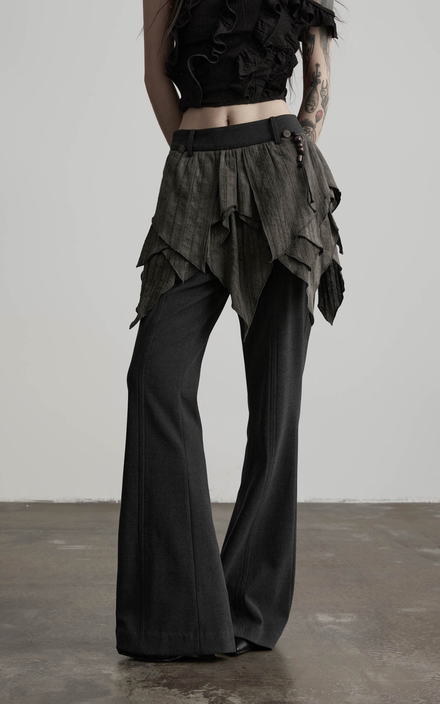 close-up of layered flare pants in black with textured draped waist detail