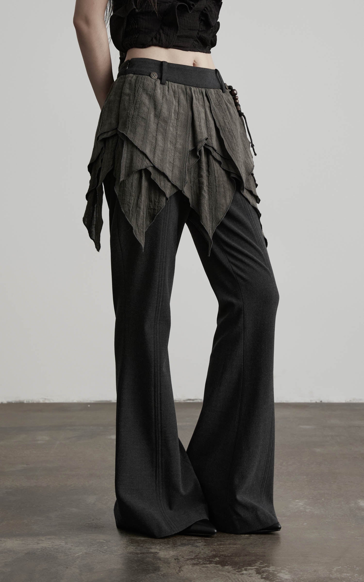 close-up of layered flare pants in black with textured draped waist detail