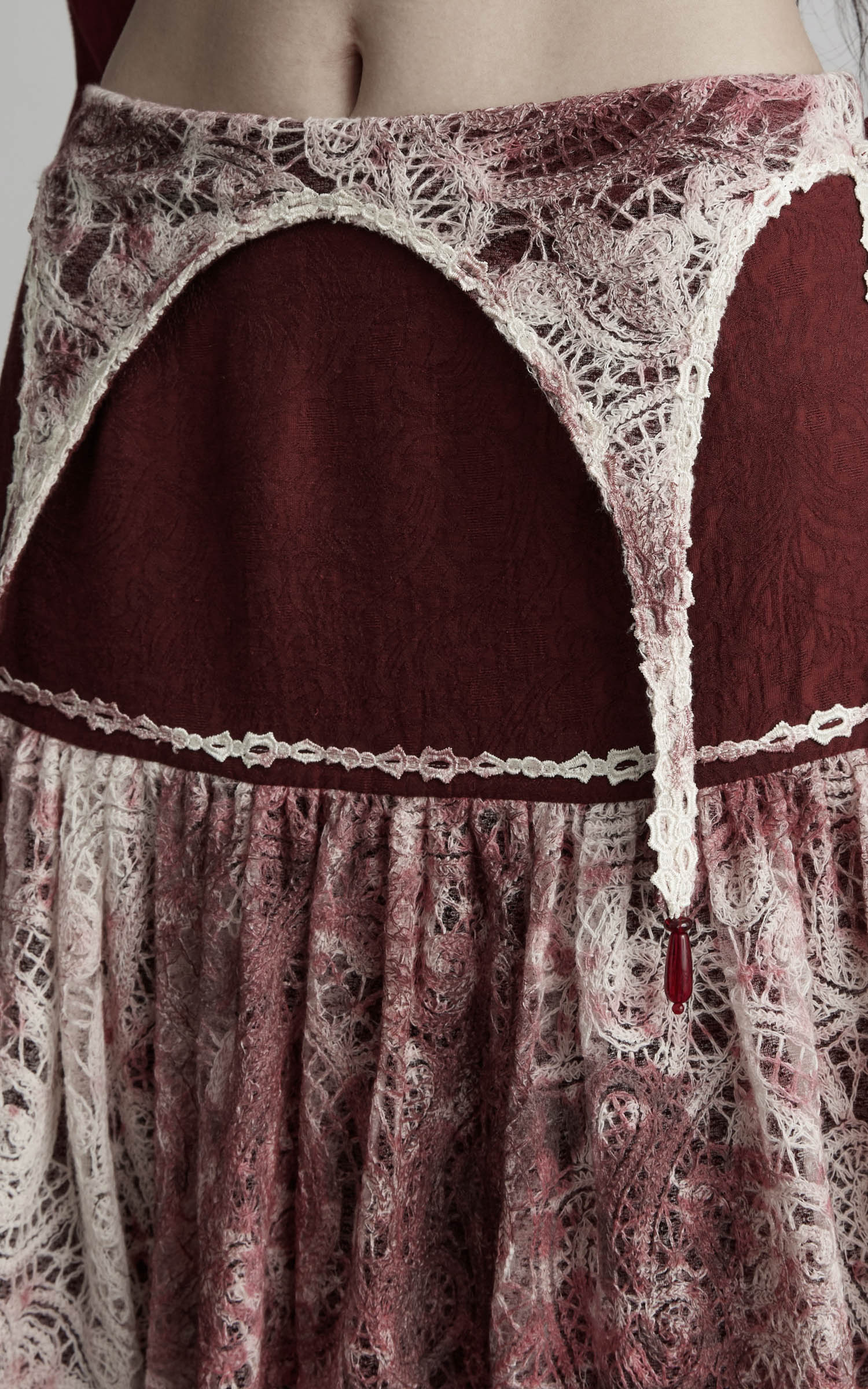 close-up of low rise maxi skirt in burgundy and ivory with curved waist