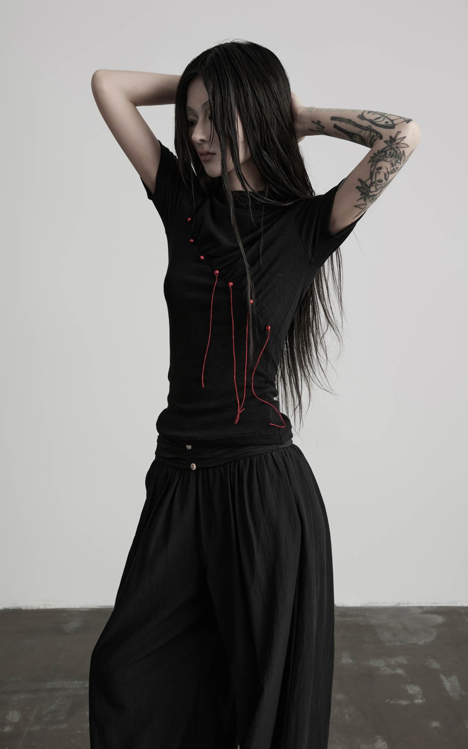 Black mock neck ruched knit T-shirt with red thread detail angled view