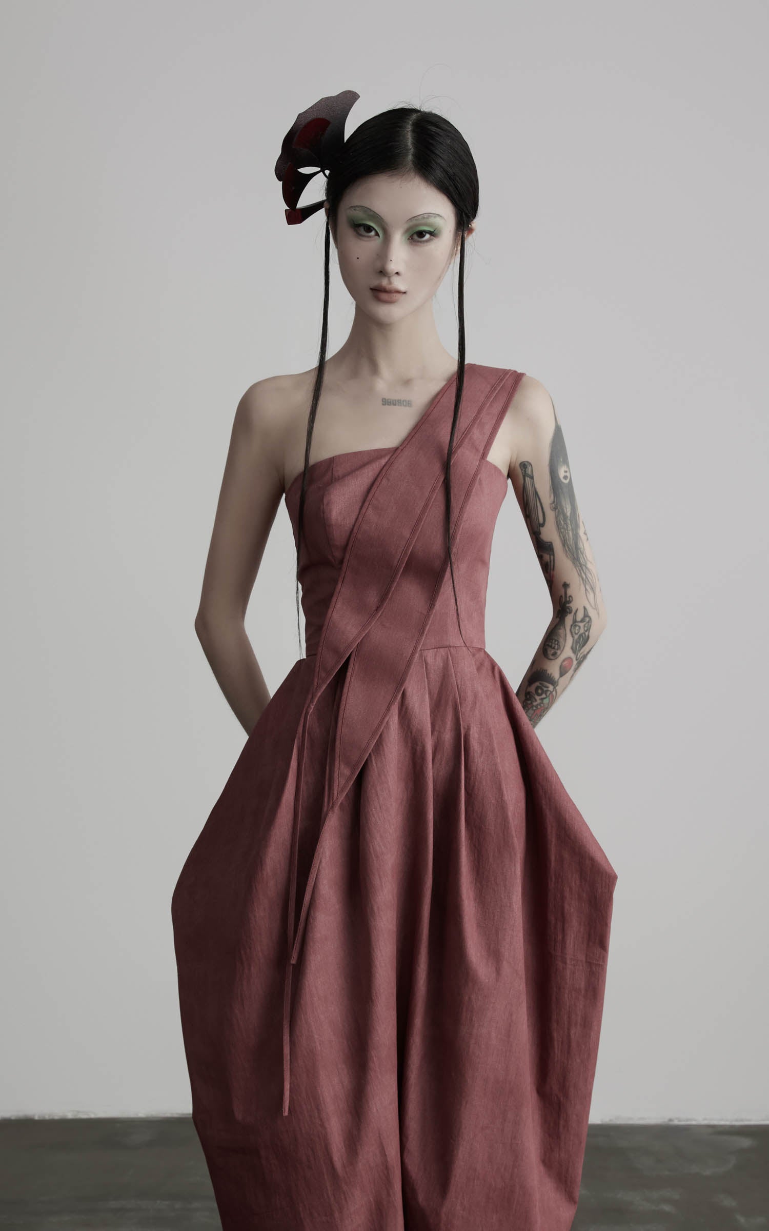Close-up of rose one-shoulder pleated maxi dress with stitched diagonal panel