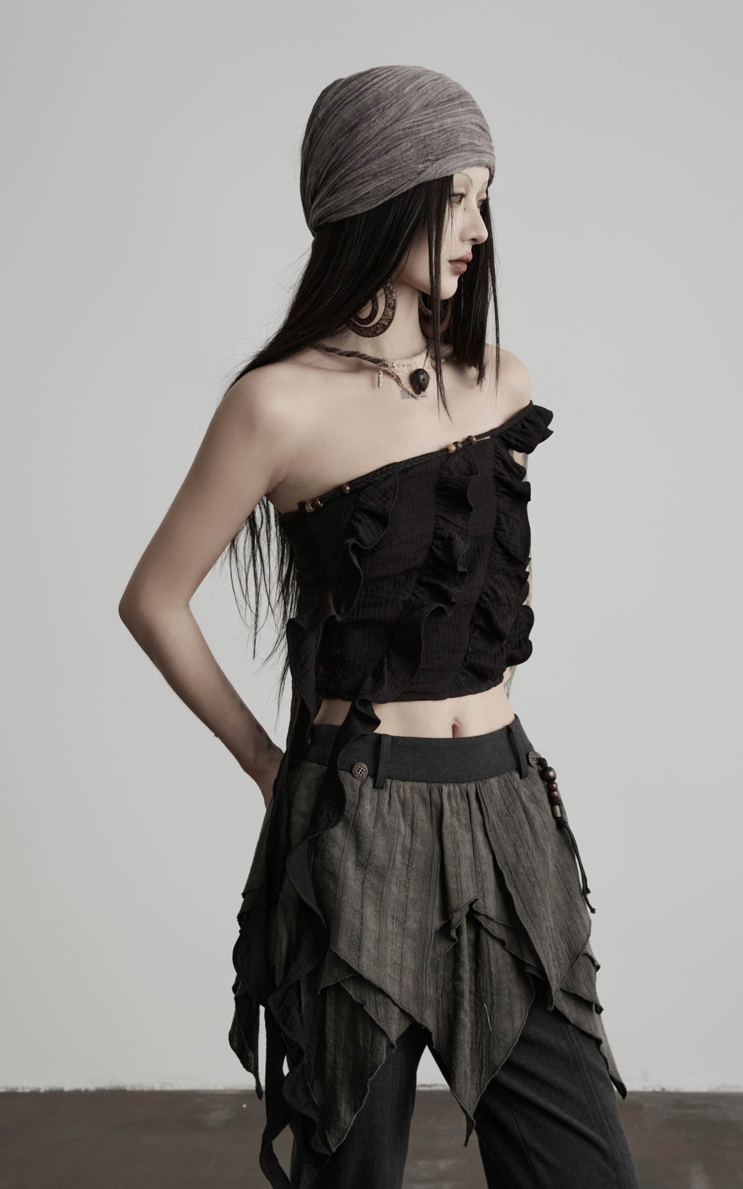 side view of black ruffled off shoulder crop top with asymmetrical neckline