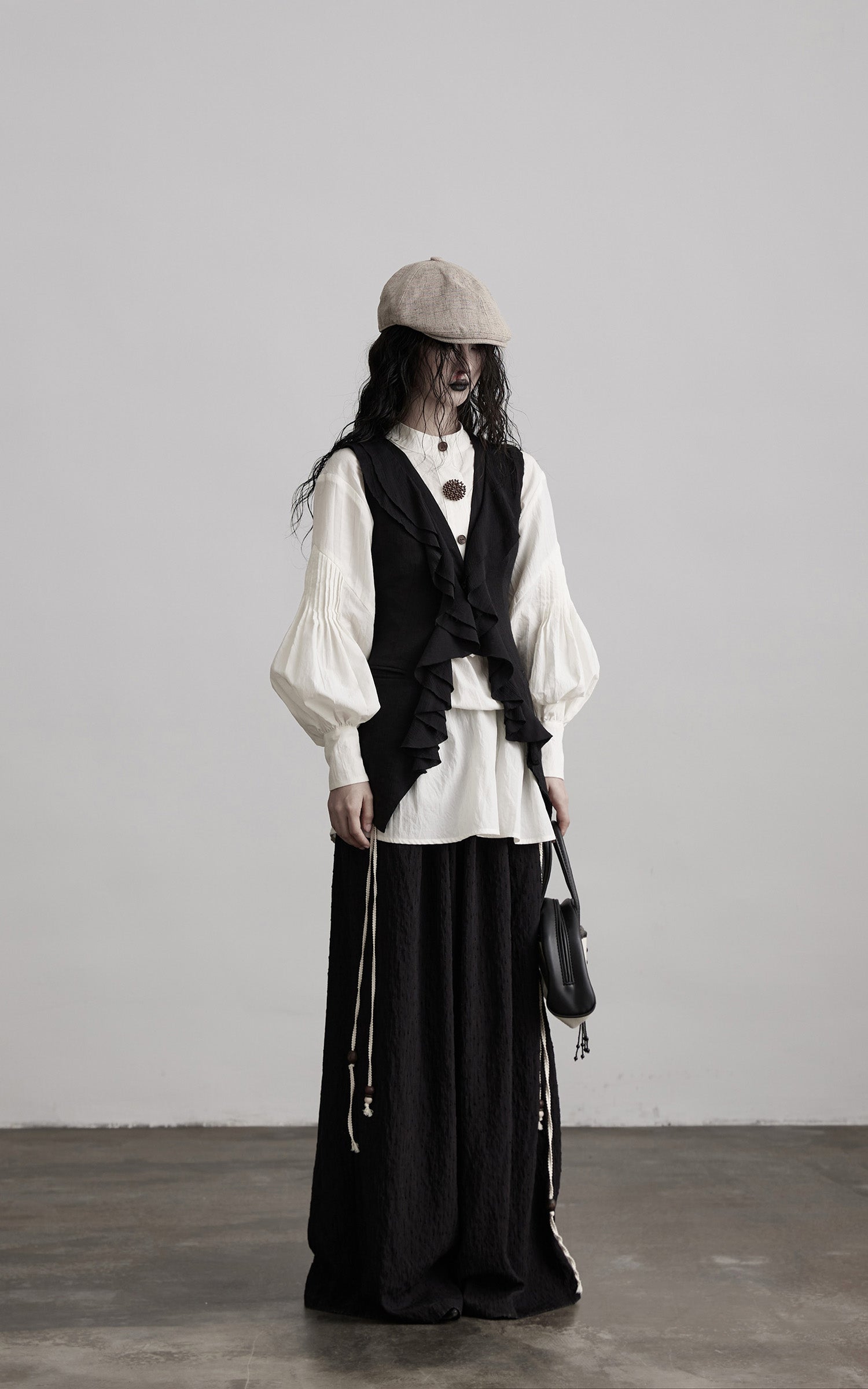 front view of black ruffled tie vest with elongated layered shape