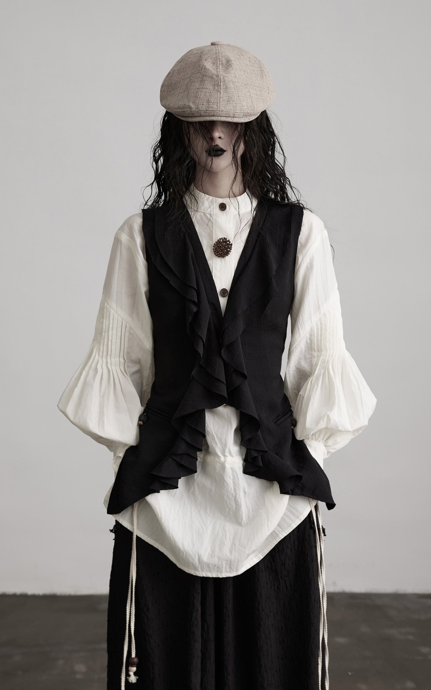 front view of black ruffled tie vest with sculpted waist fit