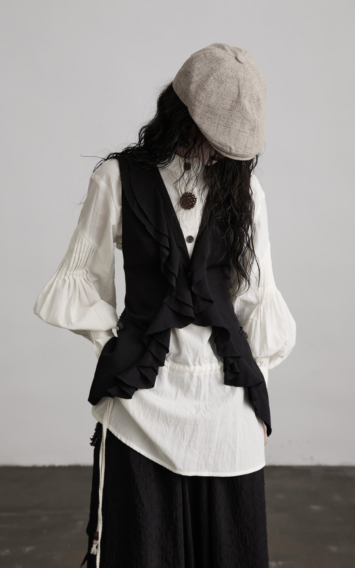 front view of black ruffled tie vest with cascading ruffle panel