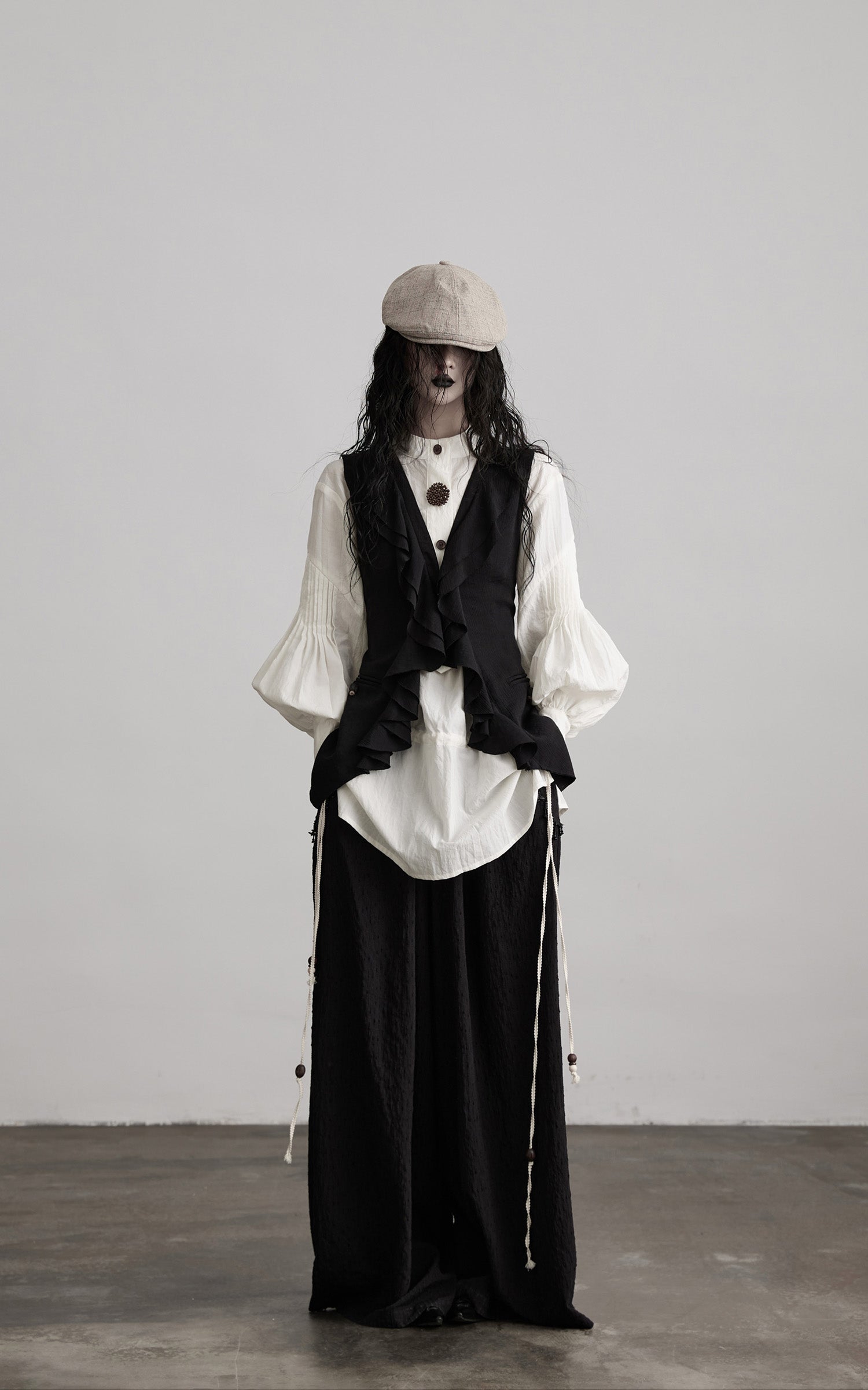 front view of black ruffled tie vest with deconstructed hem