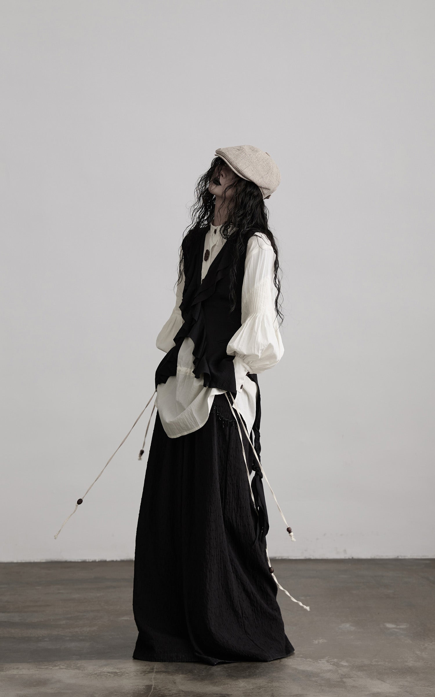 side view of black ruffled tie vest with asymmetric draped hem