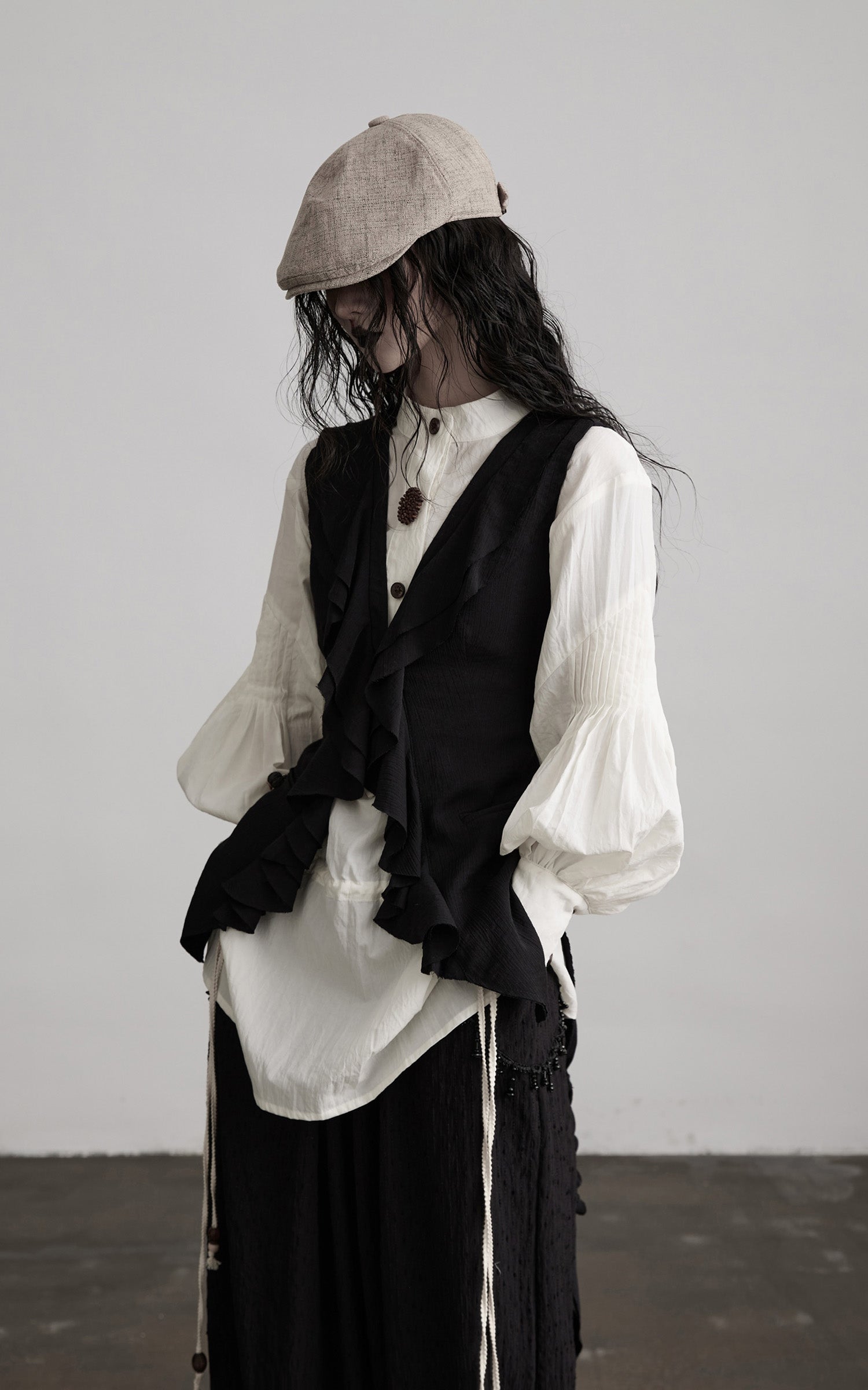 side view of black ruffled tie vest with soft structured drape