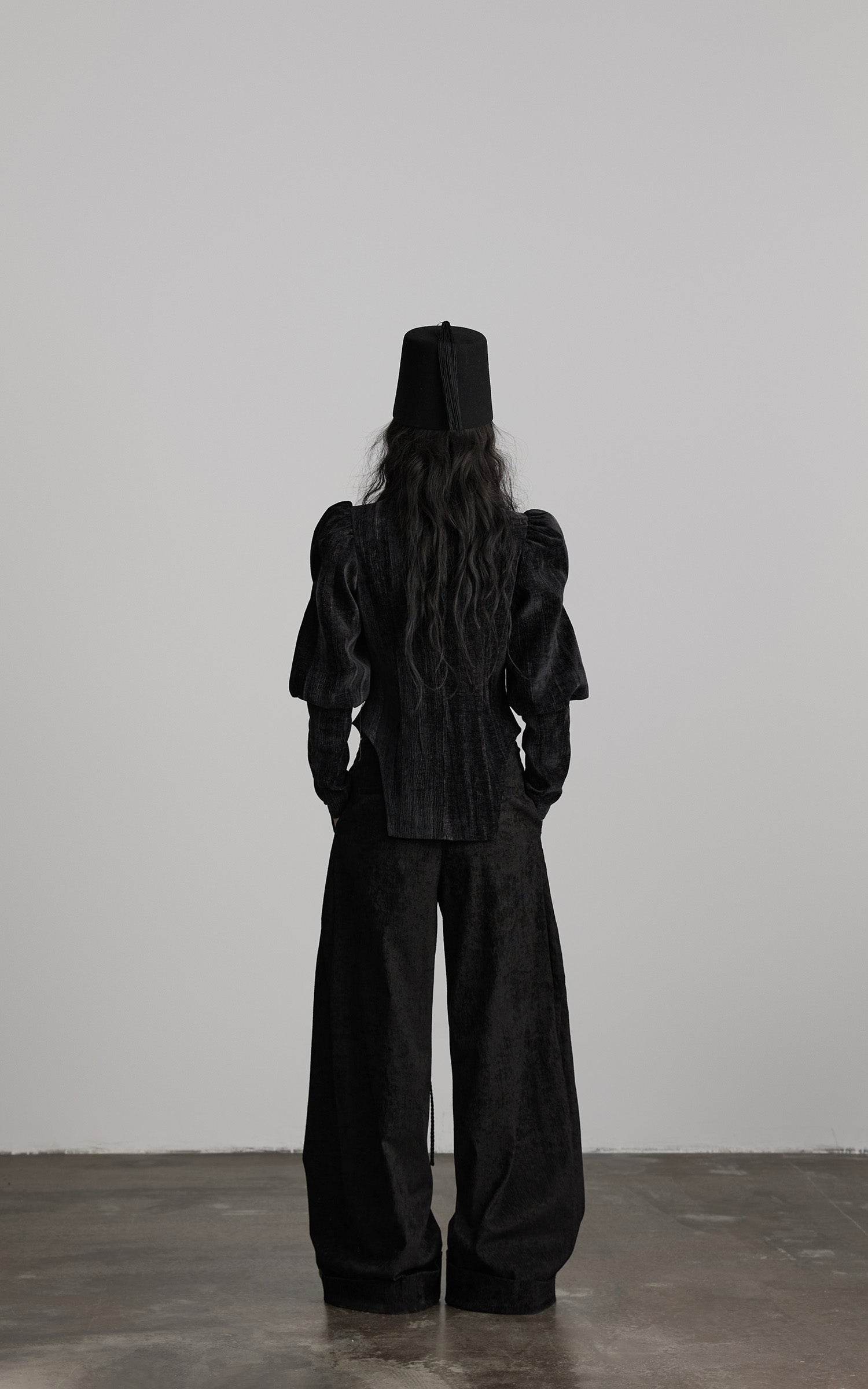 back view of black textured wide leg pants with loose structured silhouette
