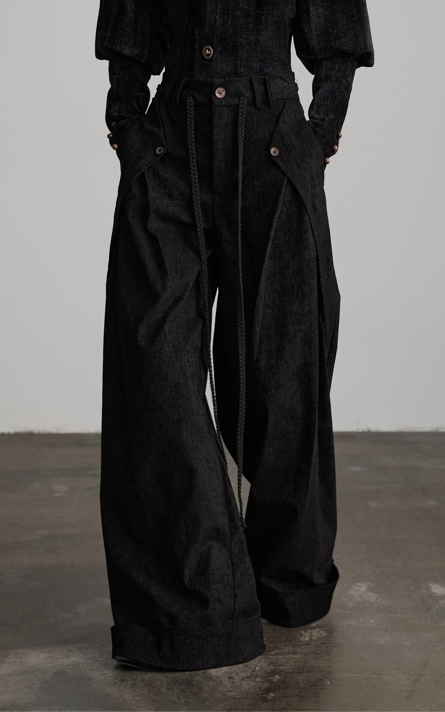 close-up of black textured wide leg pants with pleated front and rope