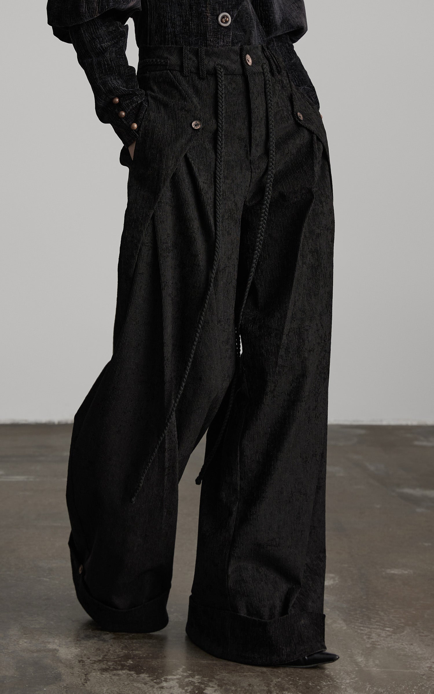 close-up of black textured wide leg pants with draped panels and rope detail